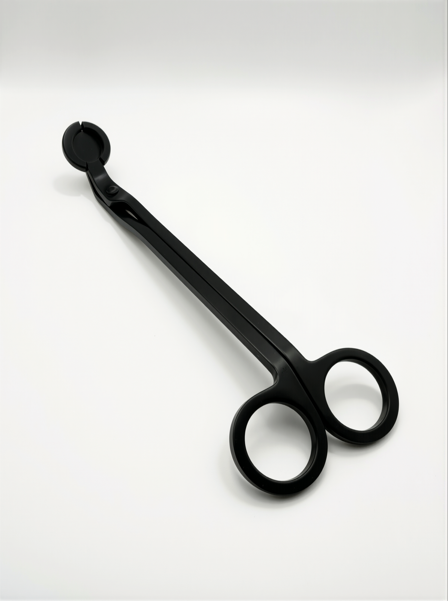 Black metal candle trimmers with curved handle on a white background