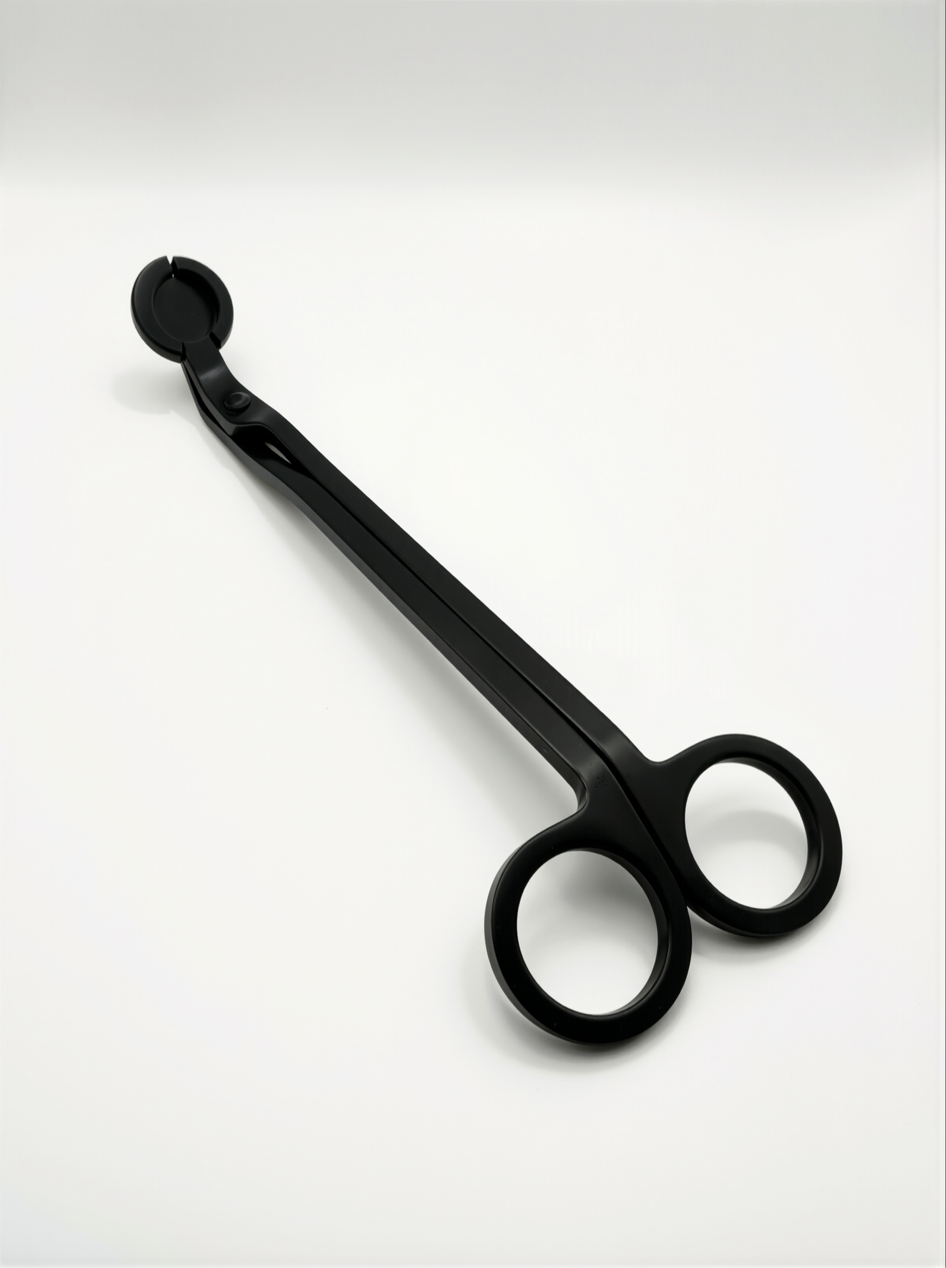 Black metal candle trimmers with curved handle on a white background