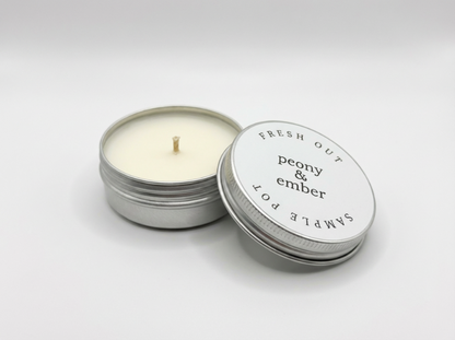 Candle sample in a tin labelled 'Fresh Out' with the brand name 'Peony & Ember' in the middle on a white background