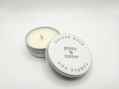 Candle sample in a tin labelled 'Golden Hour' with the brand name 'Peony & Ember' in the middle on a white background