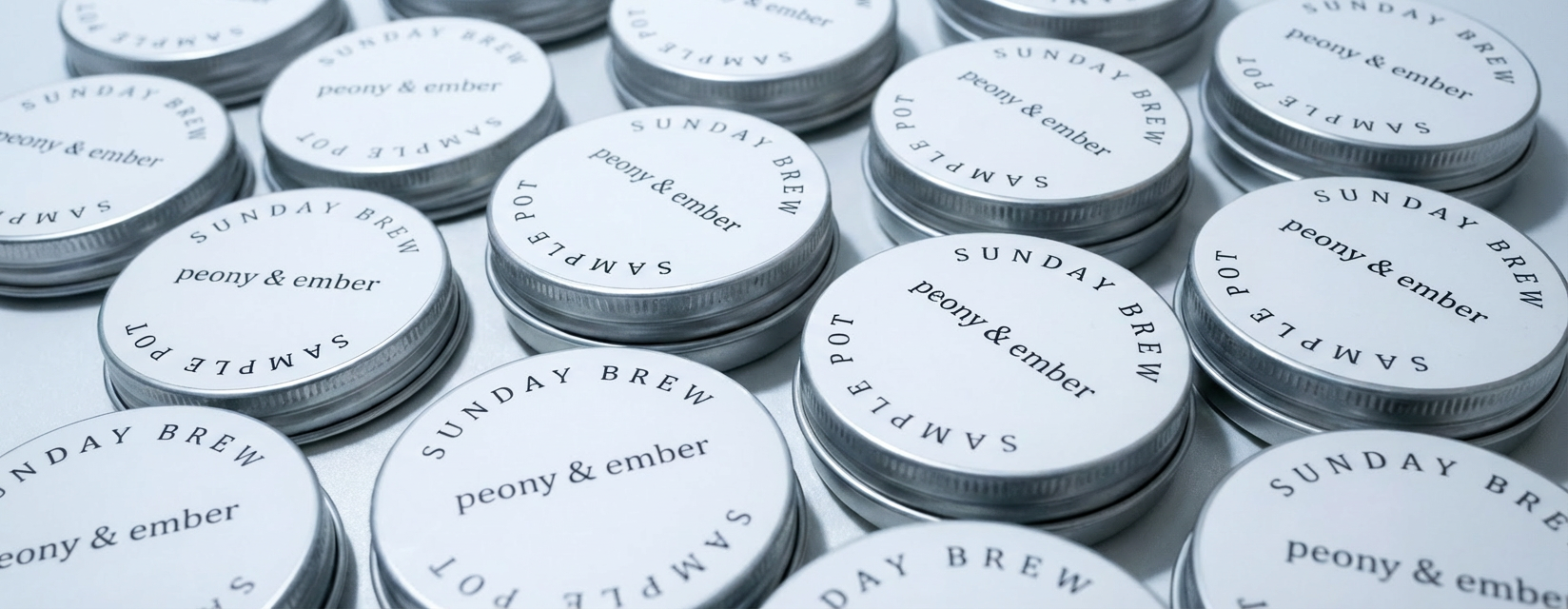 Peony & Ember candle sample  tins arranged in a flat lay. Promotional banner text reads: ‘Samples Now Available – Try 4 for £5 & redeem on your next candle.’ Luxury home fragrance brand offering affordable candle sample pots