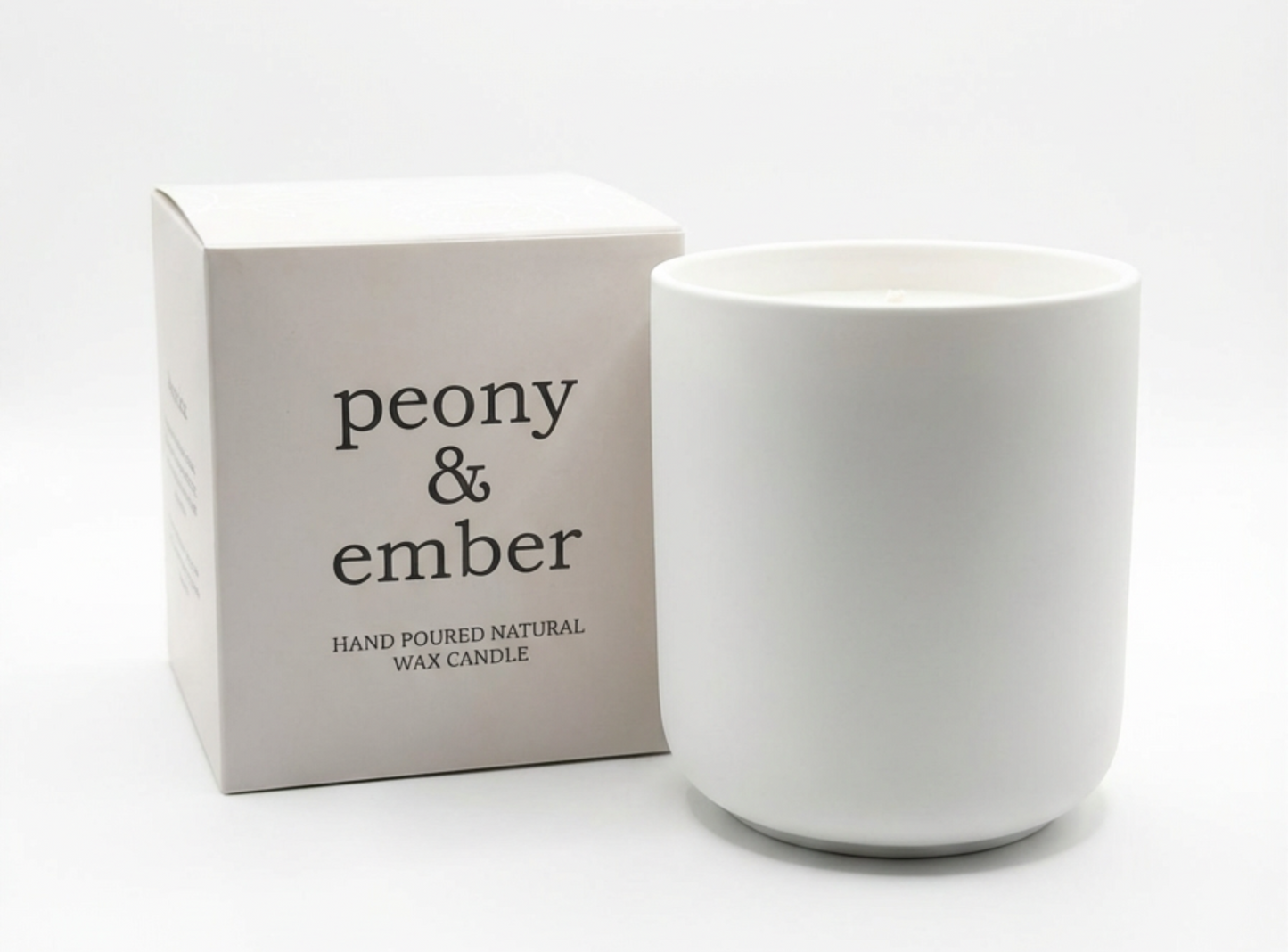 White candle with 'peony & ember' packaging on a white background