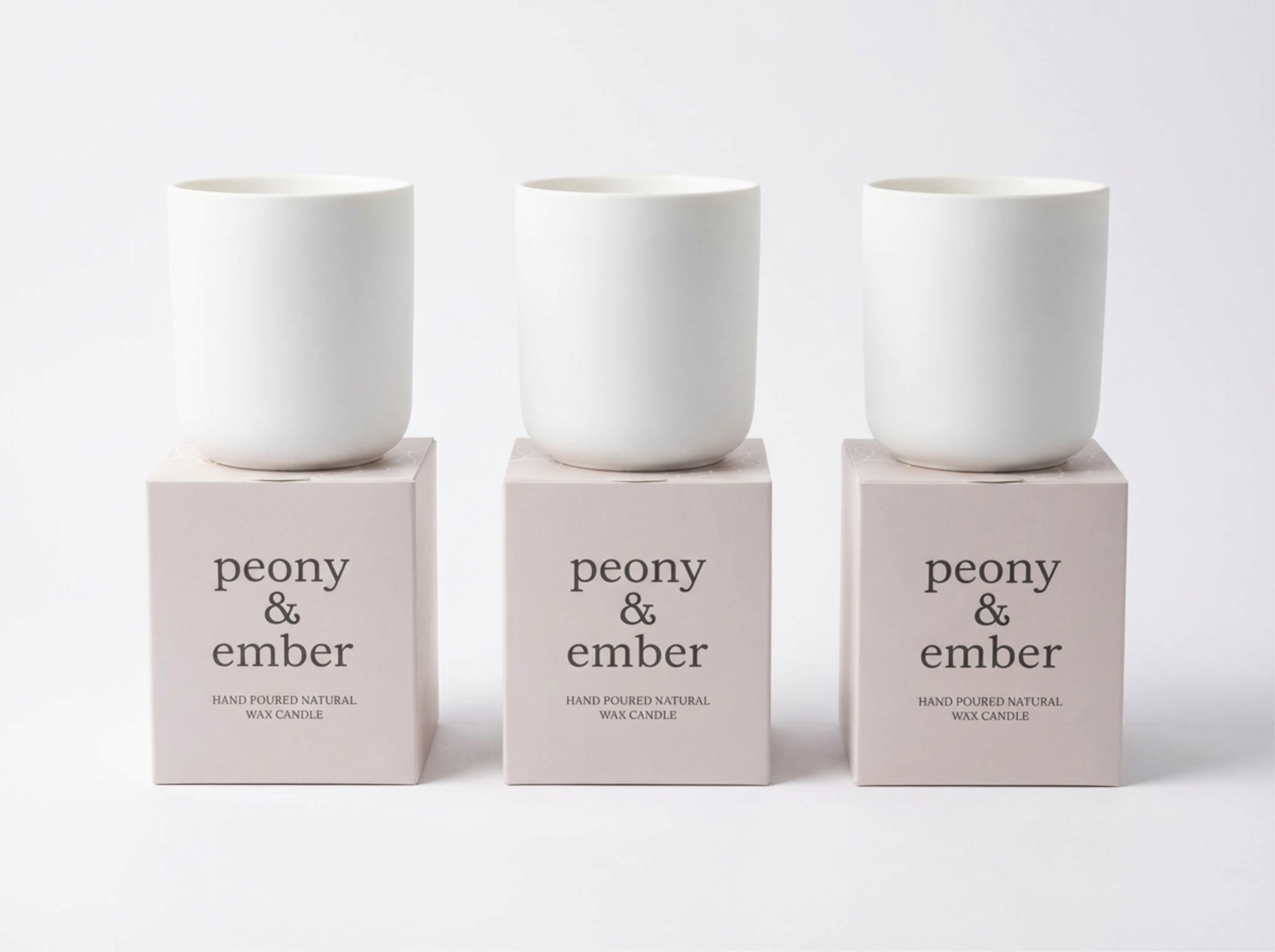 Three white candles on pink boxes with 'peony & ember' text on a white background