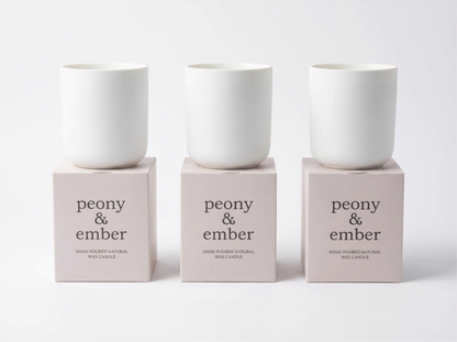 Three white candles on pink boxes with 'peony & ember' text on a white background