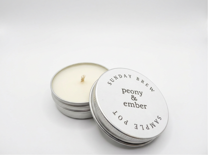 Candle sample in a tin labelled 'Sunday Brew' with the brand name 'Peony & Ember' in the middle on a white background